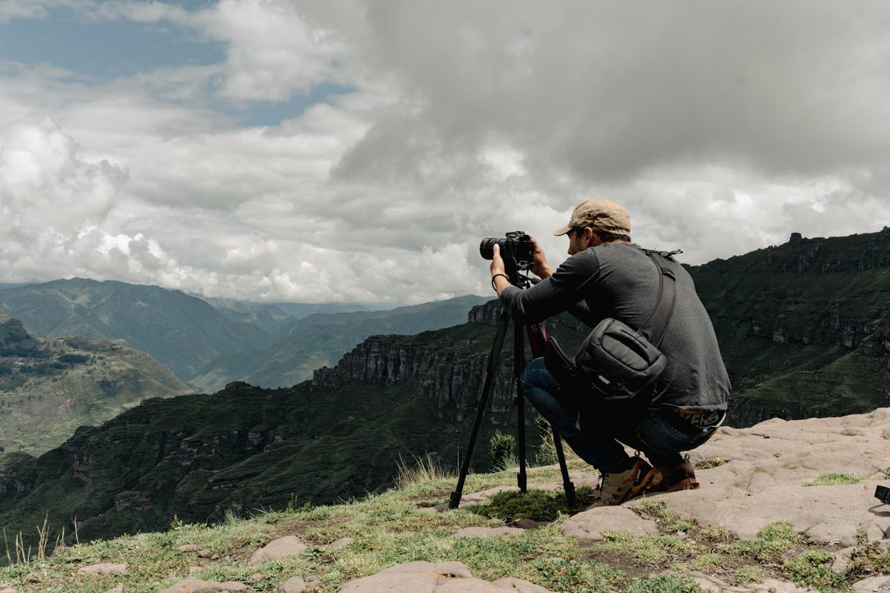 Photographer capturing scenic views at Waqrapukara ruins in Peru with tripod.