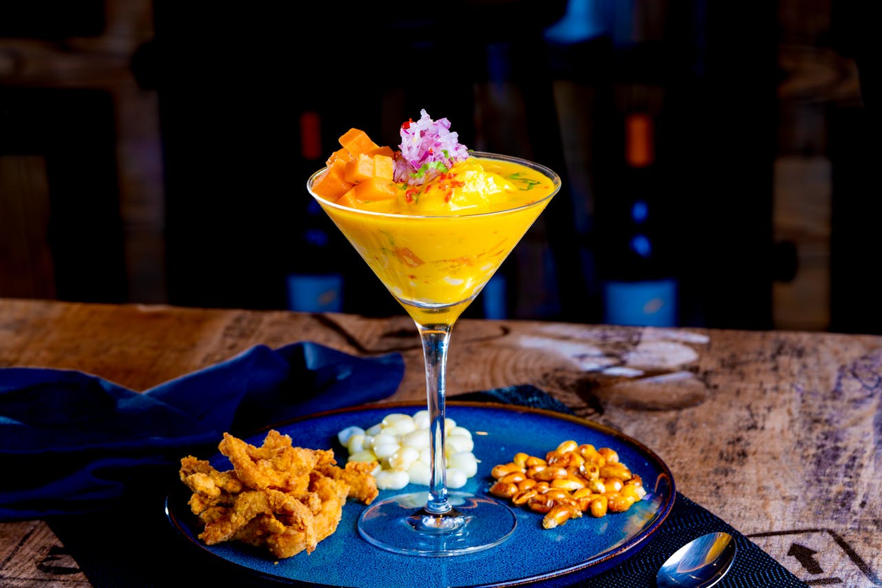 Exquisite Peruvian ceviche served in a martini glass with sides on a stylish plate.